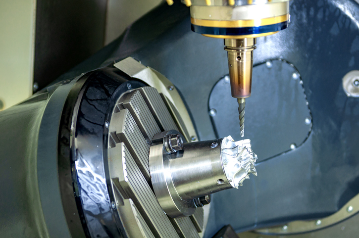 La fresatrice CNC a 5 assi che taglia la parte automobilistica in alluminio. Il processo di produzione ad alta tecnologia.